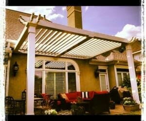 Bright day white pergola on tan house