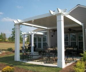 Attached white and gray pergola sitting over cement slab patio with outdoor furniture
