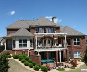 Traditional-styled, three-level brick home with second floor deck covered by white pergola