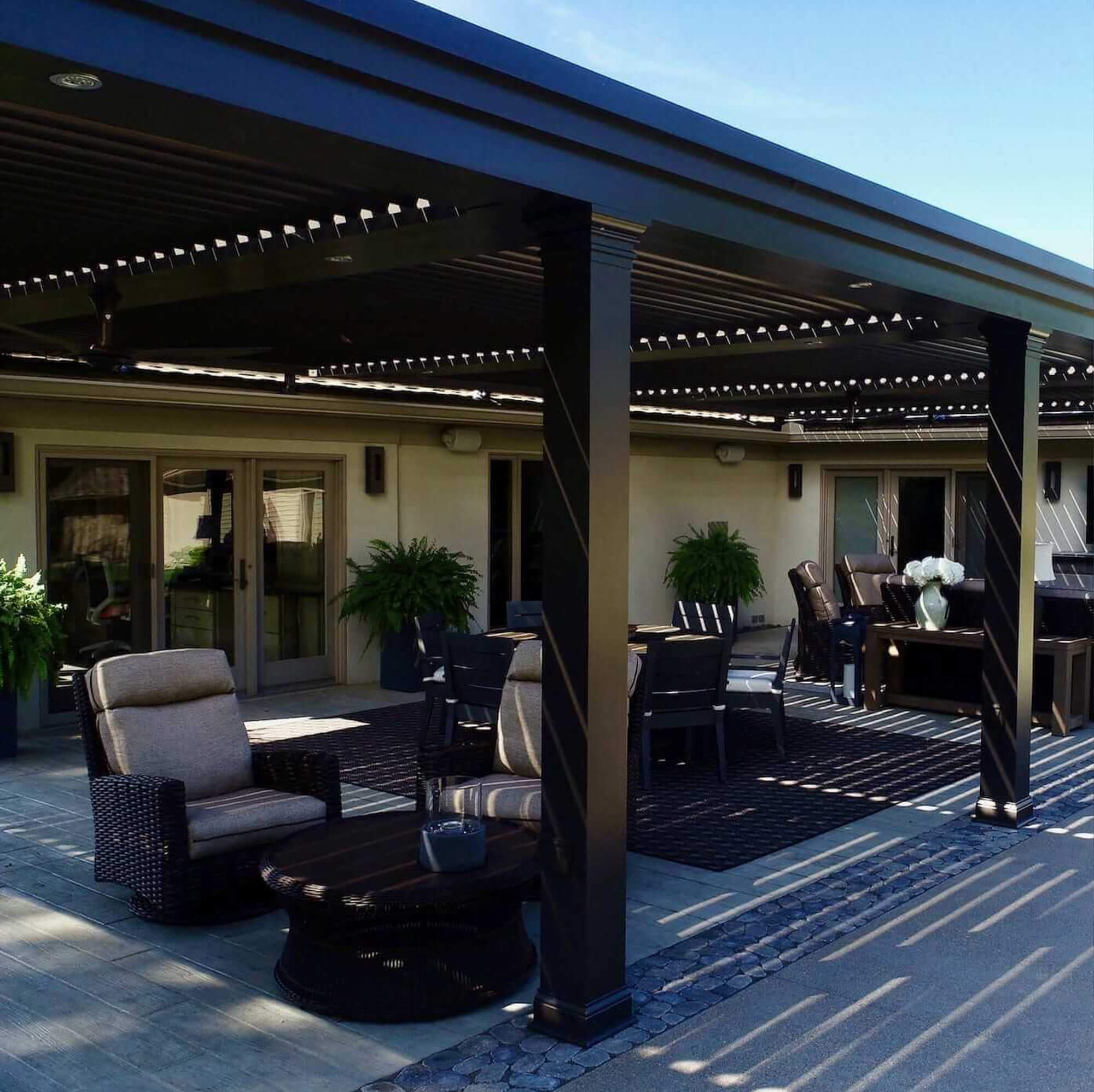 House chairs and tables under the customized black metal Pergola