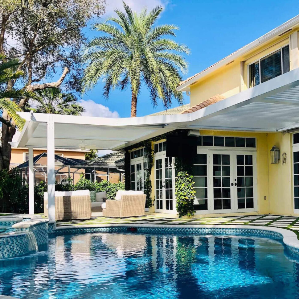 Yellow house with white outdoor pergola near pool