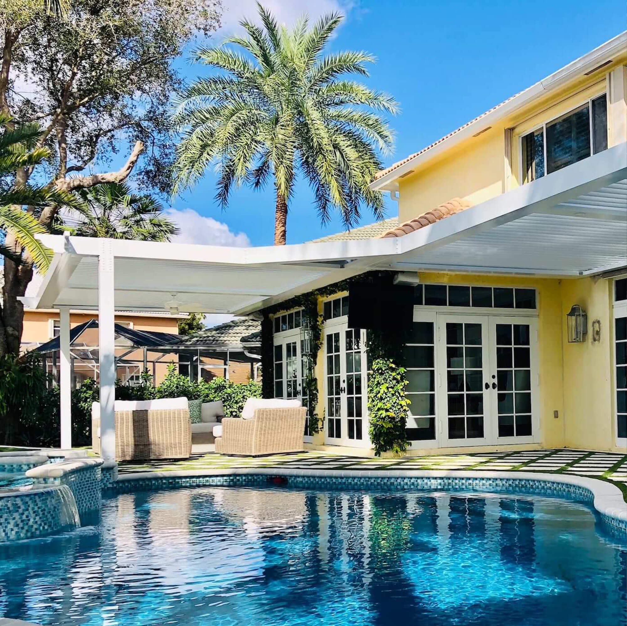 Yellow house with white outdoor pergola near pool