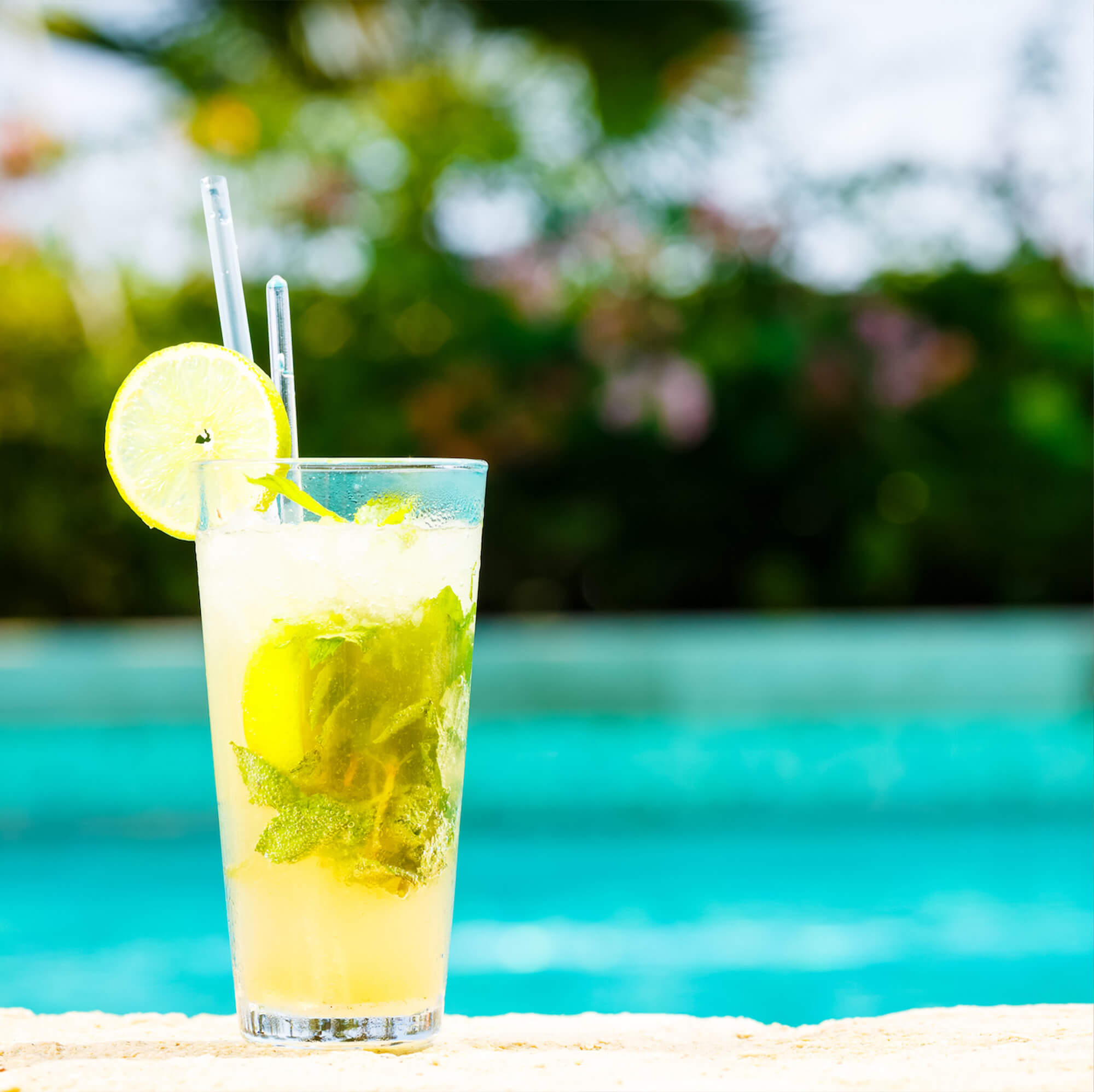 glass of cocktail drinks in the sand