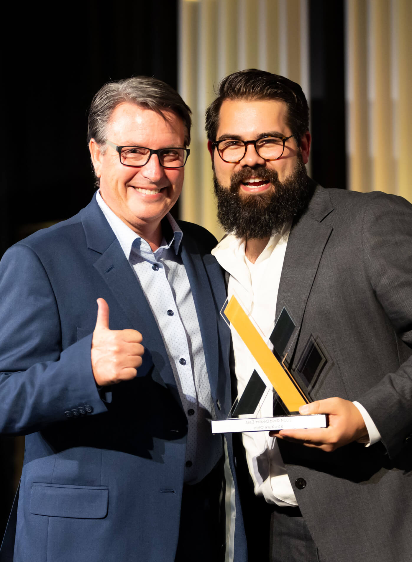 Two people hugging one another while receiving an award.