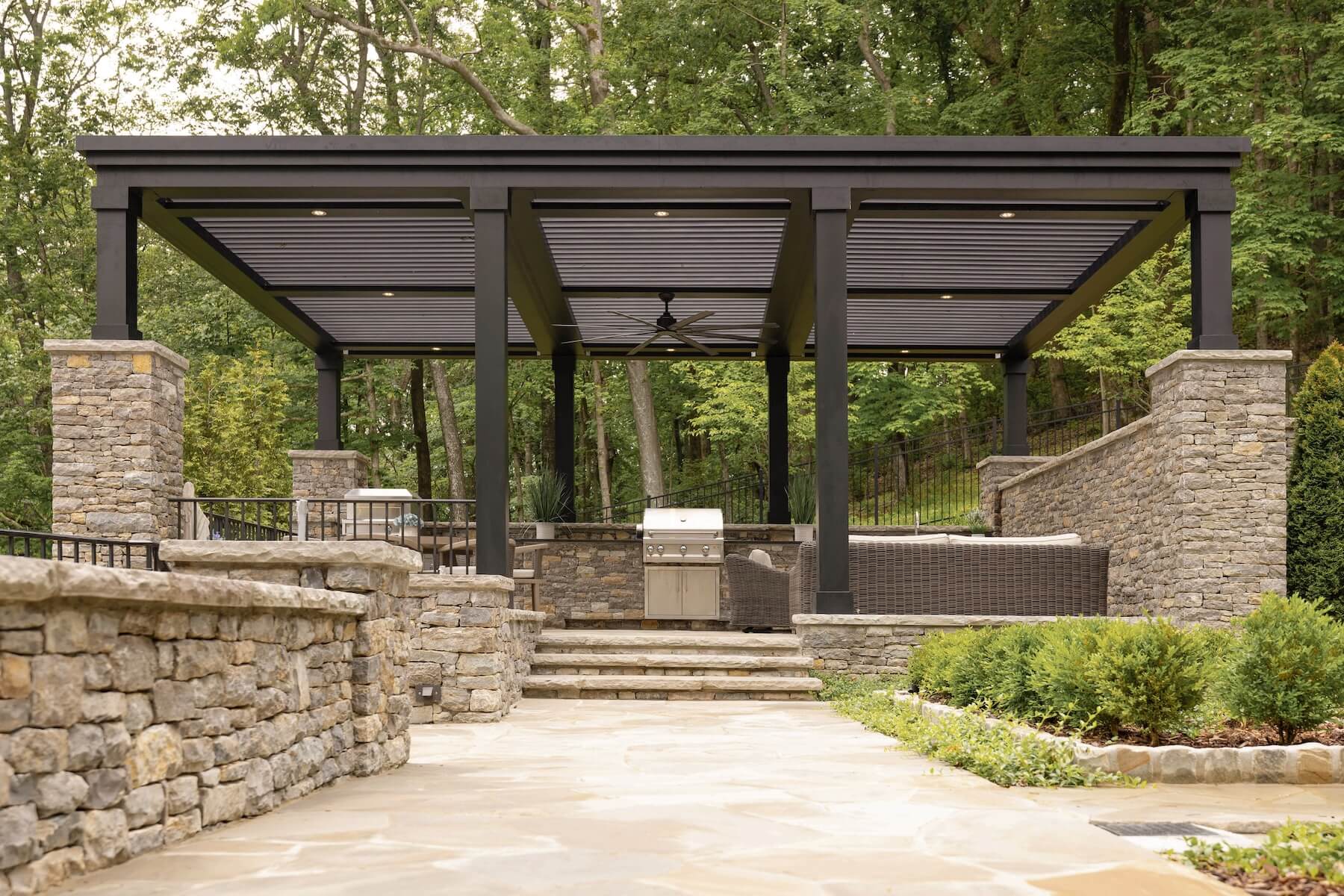 Black Pergola X custom built into natural stone patio