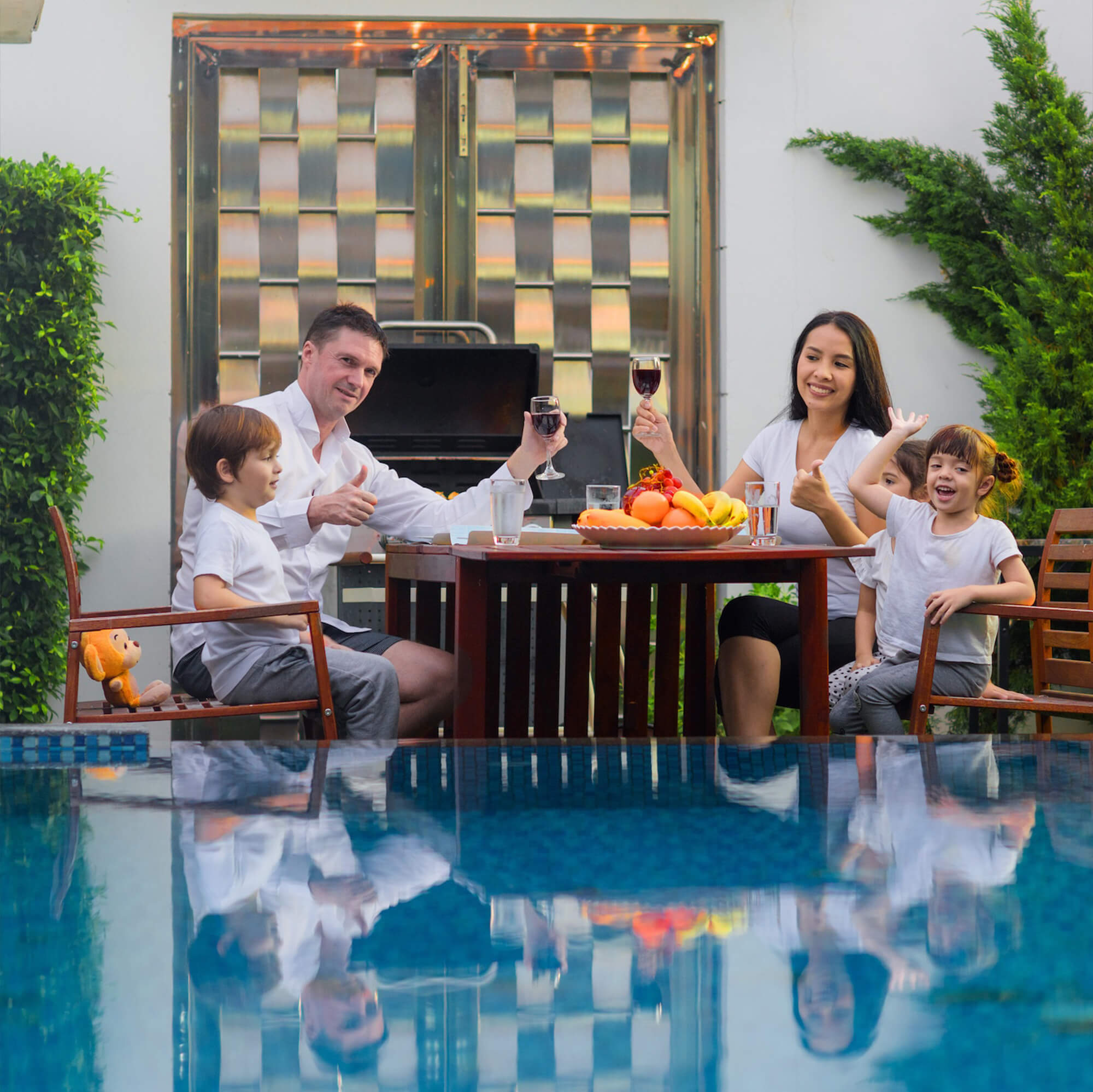 father and mother enjoying their time with three kids outdoor near the pool