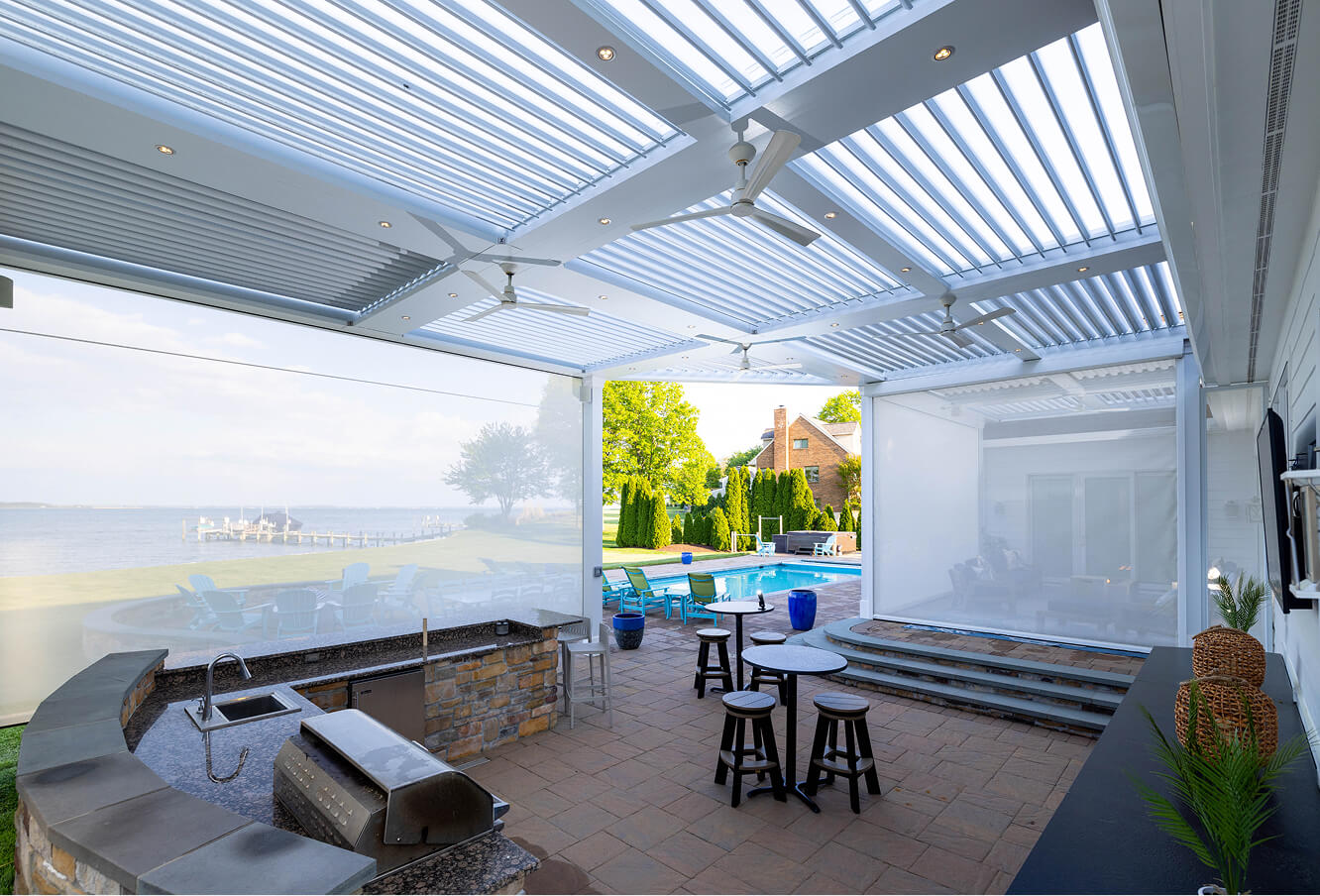 White pergola with fan in a background over an outdoor kitchen