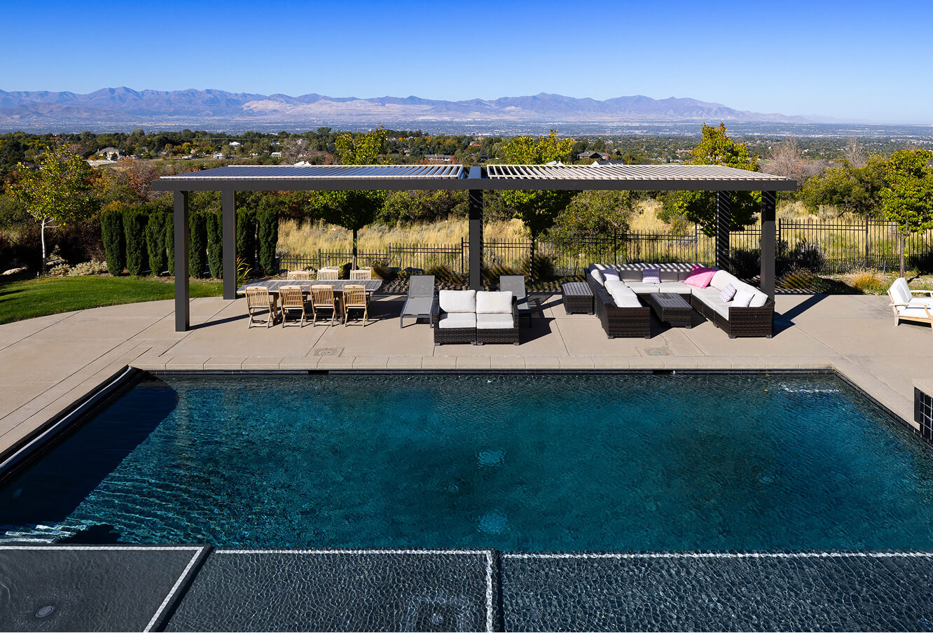 Aerial shot of multi-colored pergola over sitting area overlooking pool and mountains