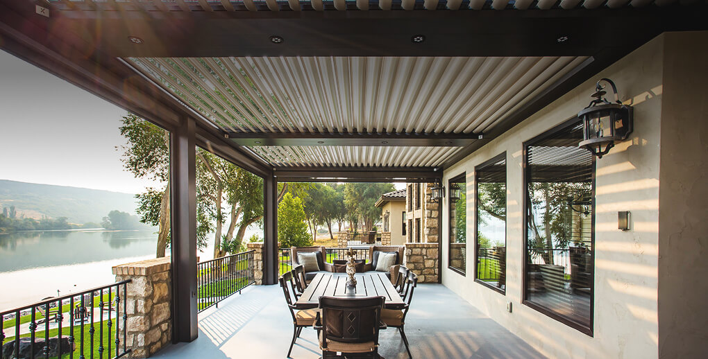 View of patio with table under a pergola overlooking a lake