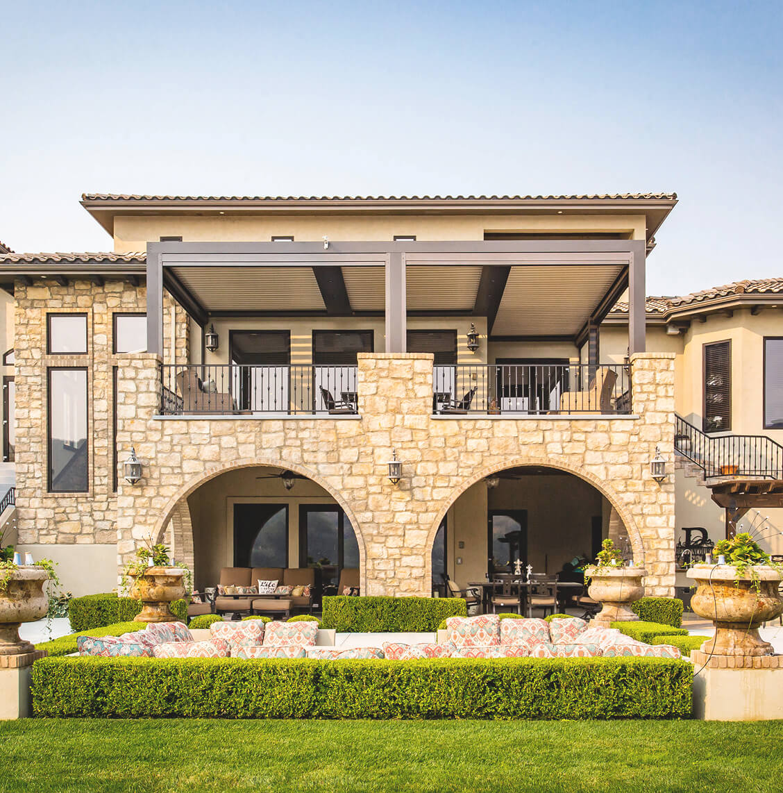 Light brick house with two level patio topped with pergola