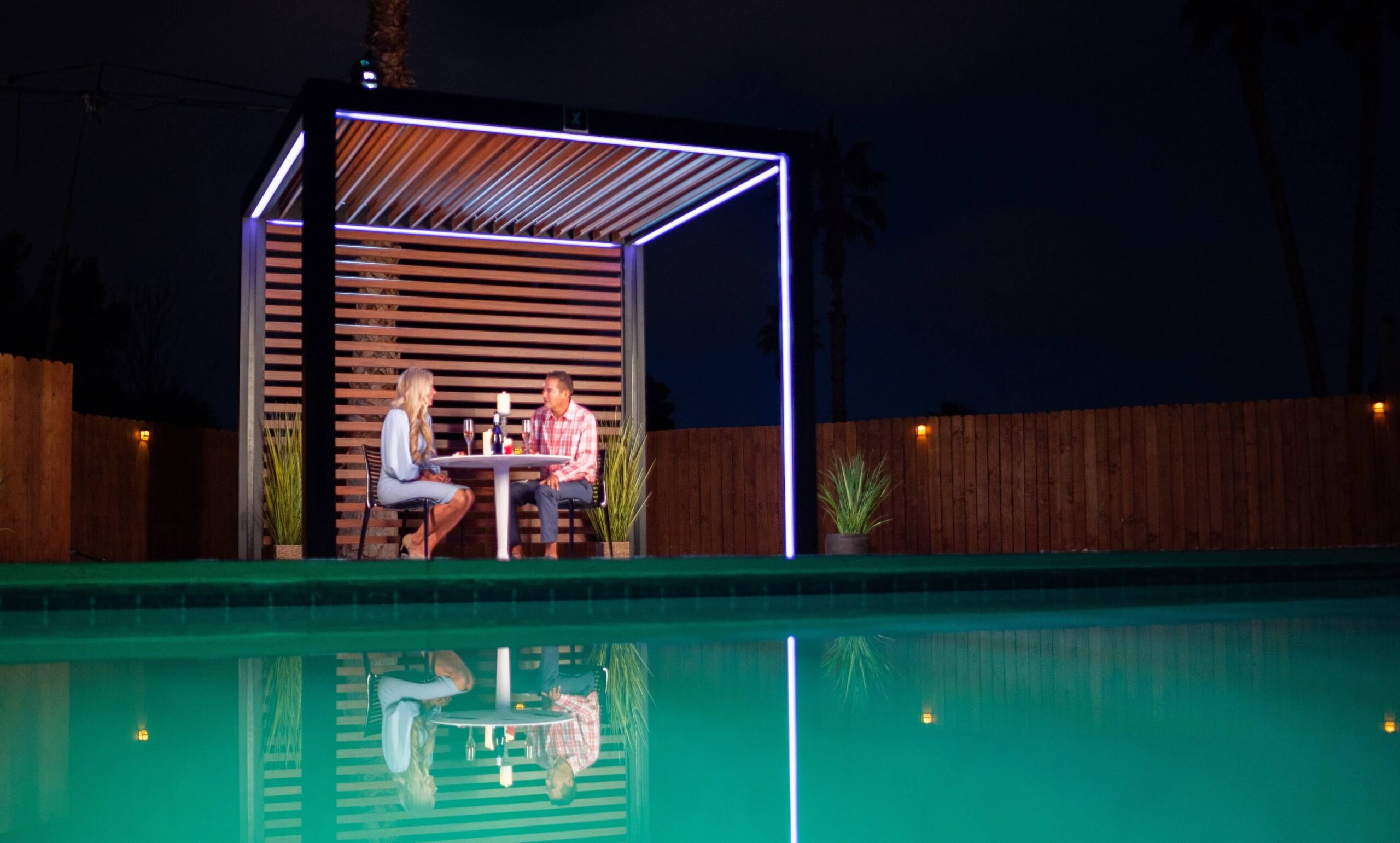 Couple sitting under a Cabana X Core+ at night beside a pool