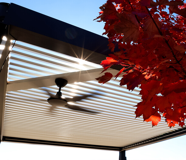 StruXure fan installed on a pergola with sunlight shining through louvers