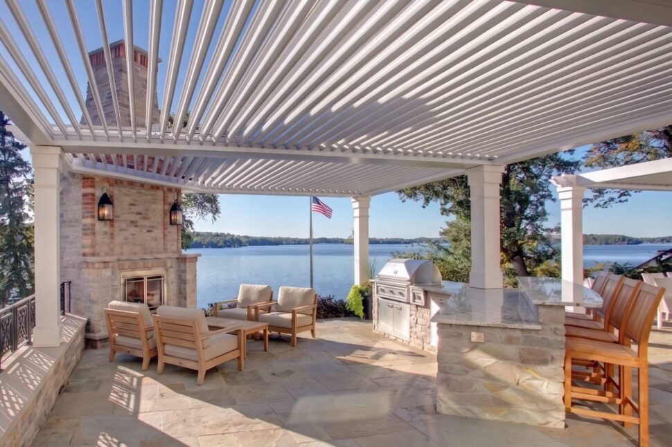 Dark StruXure Pergola X with open louvers above an outdoor fireplace and seating area