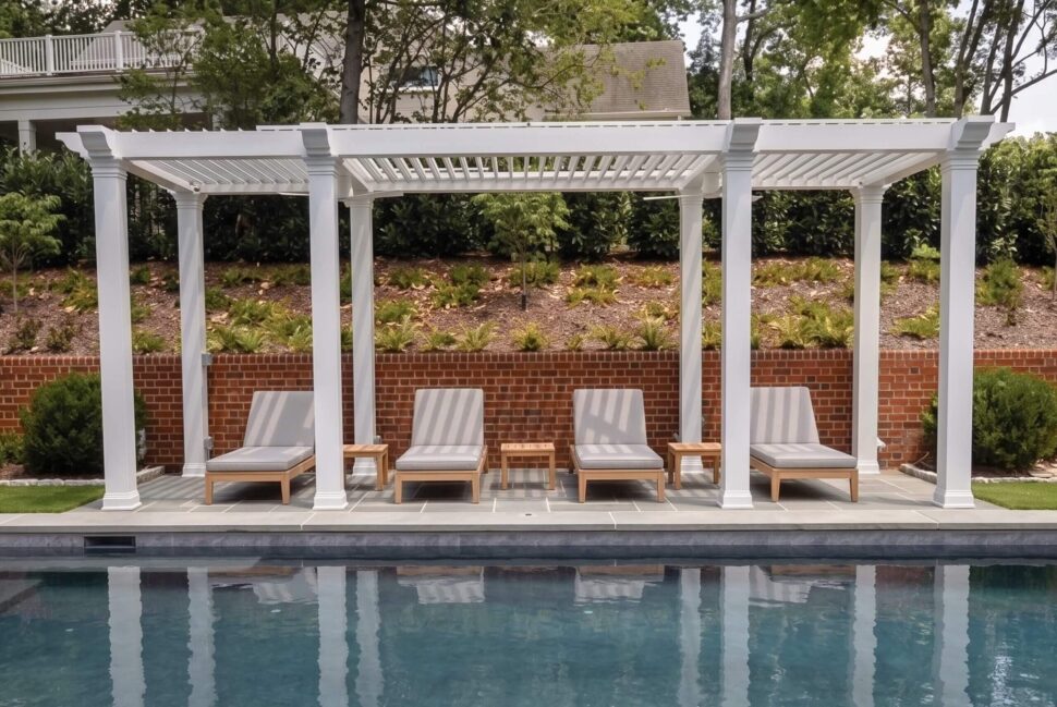 Freestanding dark StruXure Pergola X with closed louvers above poolside seating
